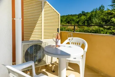 a balcony with a table and chairs and a fan at Lily Beach Resort in Sozopol