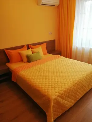 a bedroom with a bed with orange and green pillows at Sunny in Burgas City