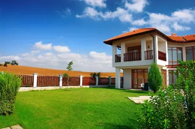a house with a green lawn in front of a fence at Generaator House in Aheloy