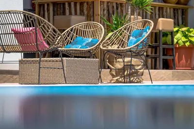 three chairs with blue pillows sitting next to a pool at JI HOTEL in Sozopol