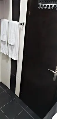 a bathroom with a black door and white towels at St George Apartcomplex in Shkorpilovtsi
