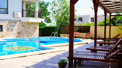 a swimming pool with two benches next to a house at Комплекс Бяла Виста до Плажа - Complex Byala Vista near the beach in Byala