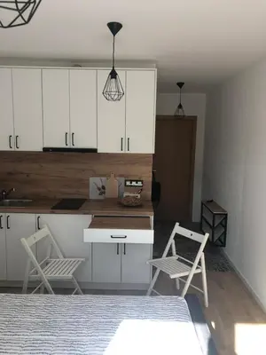 a kitchen with white cabinets and two chairs and a table at Loli’s Beach Studio in Burgas City