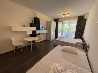 a room with two beds and a desk and a table at MM Complex Dimitrovi in Primorsko