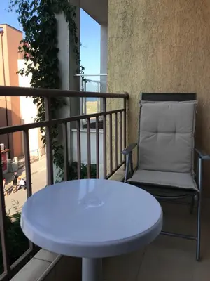 a white table and a chair on a balcony at Familienapartment am Strand in Primorsko in Primorsko