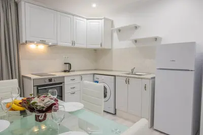 a kitchen with white cabinets and a glass table at Vip Luxury APARTMENT in Burgas City