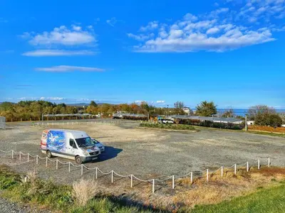 a van parked in a parking lot next to a fence at бунгала и kаравани Дрийм къмпинг Гардения in Kiten