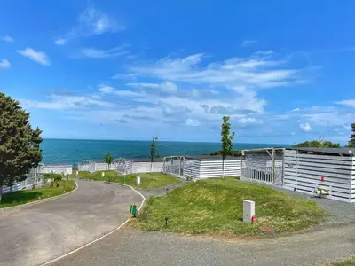 a road leading to a building with the ocean in the background at бунгала и kаравани Дрийм къмпинг Гардения in Kiten