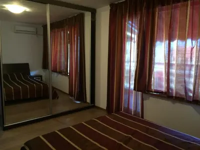 a bedroom with a mirror and a bed and a window at 2-х комнатные апартаменты в г.Поморие Болгария in Pomorie
