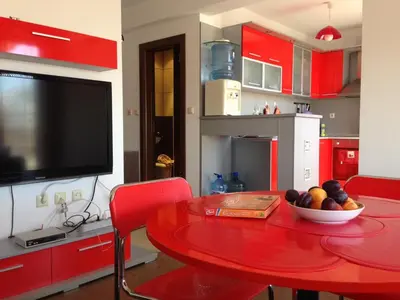 a kitchen with a red table with a bowl of fruit on it at 2-х комнатные апартаменты в г.Поморие Болгария in Pomorie