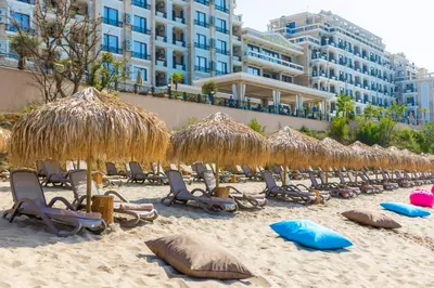a group of chairs and straw umbrellas on a beach at Onyx Beach Residence - Free Beach Access & Parking in Sveti Vlas