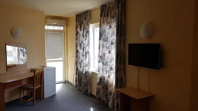 a room with a television and a desk and a window at Krasi Hotel in Ravda
