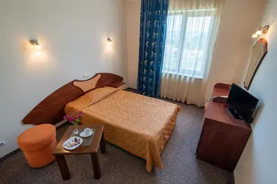 a small hotel room with a bed and a television at Adamo Hotel in Varna City