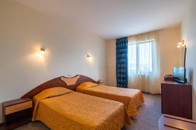 a hotel room with two beds and a television at Adamo Hotel in Varna City