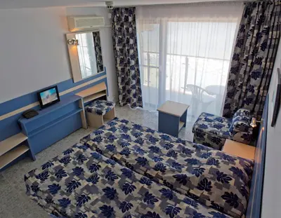 a bedroom with a bed and a chair and a window at Palace Hotel - Half Board in Sunny Beach