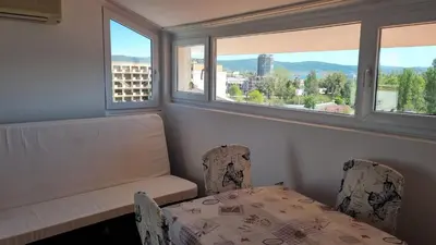 a room with a table and chairs and two windows at Penthaus Cacao Beach in Sunny Beach