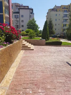 a brick walkway in a park with flowers and buildings at Studios in Complex Elit 4 in Sunny Beach