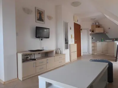 a living room with a table and a tv on the wall at Studio Stoianovi in Nesebar