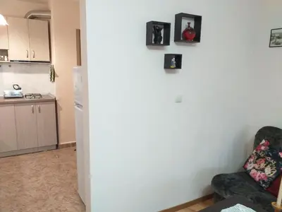 a living room with a chair and a kitchen at Апартамент Термите in Varna City