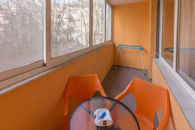 a room with orange chairs and a table and windows at Kapriz - 2 beds aptmnt near the beach in Varna City
