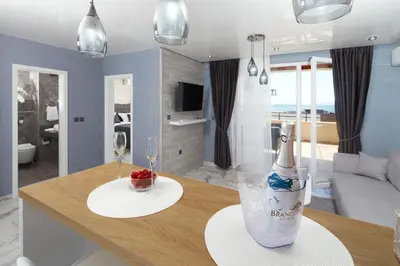 a living room with a table with a bottle of wine at Niko's Apartments Deluxe in Nesebar