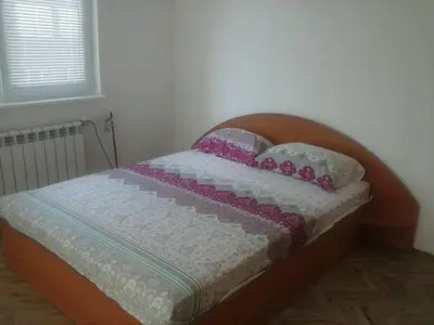 a small bedroom with a bed with a wooden headboard at Семеен хотел Стаси in Pomorie