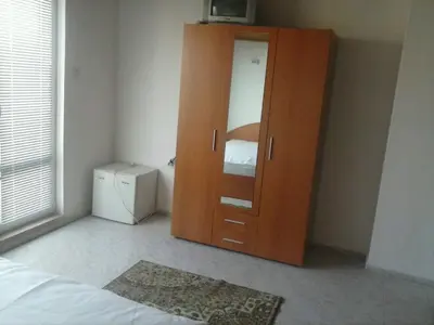 a bedroom with a wooden cabinet and a bed at Семеен хотел Стаси in Pomorie