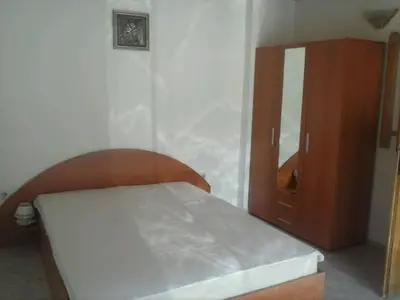 a bedroom with a bed and a wooden cabinet at Семеен хотел Стаси in Pomorie