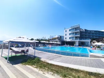 a swimming pool with chairs and umbrellas next to a building at Moonlight Hotel - All Inclusive in Sveti Vlas