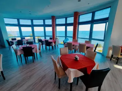 a dining room with tables and chairs and windows at Moonlight Hotel - All Inclusive in Sveti Vlas
