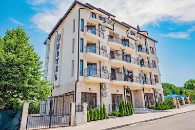 a white building with balconies on a street at Hotel Santa Maria in Obzor