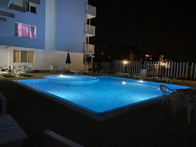 a swimming pool in front of a building at night at Апартамент Морска Звезда in Nesebar