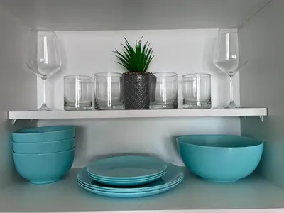 a shelf with blue bowls and glasses and a plant at PARADISO 'В' 311 Private Studio Nesebar in Nesebar