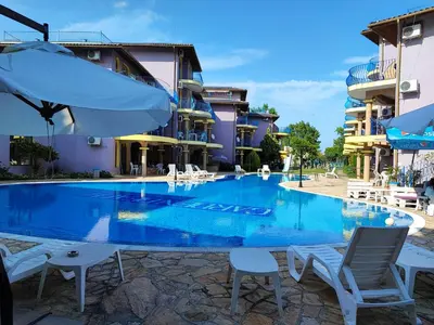 a large swimming pool with chairs and an umbrella at Гардън Бийч - НЕДЯЛКОВИ in Sozopol