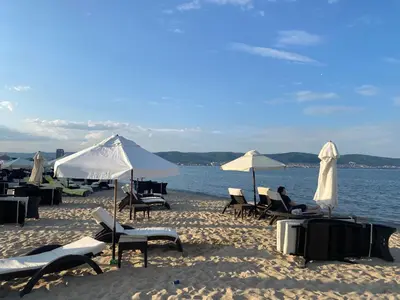 a group of chairs and umbrellas on a beach at FORT NOKS NESSEBAR B2-216 Studio SUNNY BEACH in Sunny Beach