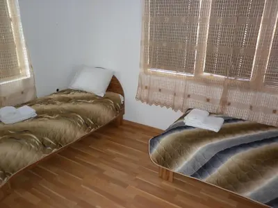 two beds in a room with two windows at Ivanova Cheshma Guest House in Varna City