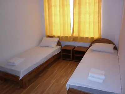 two beds in a small room with a window at Ivanova Cheshma Guest House in Varna City