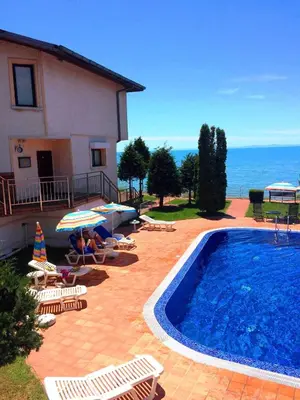 a villa with a swimming pool and chairs and a house at Sun Palace apartments in Sveti Vlas