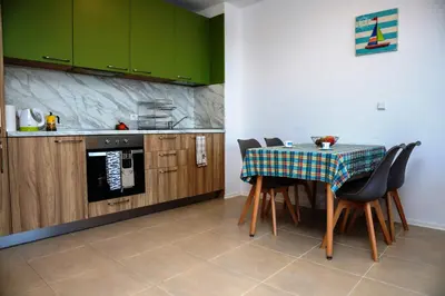 a kitchen with a table and some green cabinets at Green Life One-Bedroom Apartment with Sea View by Flаt Manаger in Sozopol