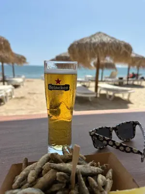 a glass of beer sitting on a table with a plate of food at Аппартамент в Триумфе Святой Влас 300м от моря, бассейн. in Sveti Vlas