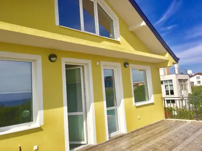 a yellow house with windows on a wooden deck at Luxury House In Chervenka next to Gradina beach in Chernomorets