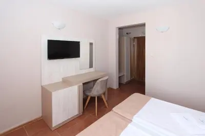 a bedroom with a desk and a tv on a wall at Hotel PERLA BEACH in Sozopol