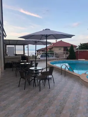 a patio with tables and umbrellas next to a pool at Hotel PERLA BEACH in Sozopol