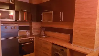 a kitchen with wooden cabinets and a sink and a refrigerator at VIP Sunrise Apartment in Lozenets