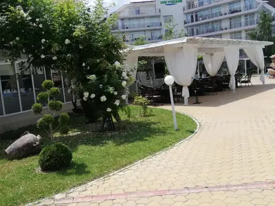 a pavilion with white curtains and a table and chairs at Debbies 2 bed apart with pool and garden views in Sunny Beach