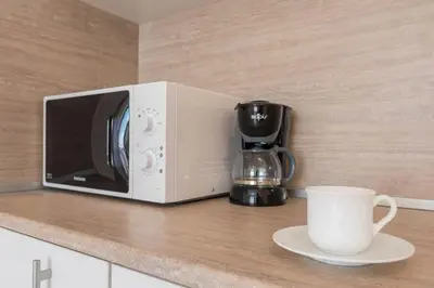 a white microwave on a counter with a cup of coffee at Blue Lagoon Seafront Apartments in Varna City