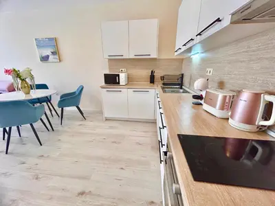 a kitchen with white cabinets and a table with chairs at Blue Lagoon Seafront Apartments in Varna City