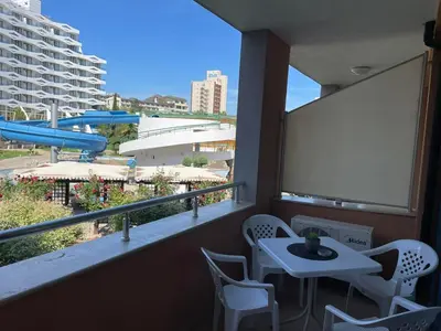 a white table and chairs on a balcony with a screen at Apartment in Trakia Plaza complex in Sunny Beach