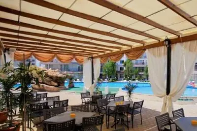 a patio with tables and chairs and a swimming pool at Yves 2 Bed apart at Sun Village Sunny Beach not far away from the sea in Sunny Beach