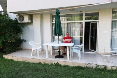 a man sitting at a table with an umbrella at Yves 2 Bed apart at Sun Village Sunny Beach not far away from the sea in Sunny Beach
